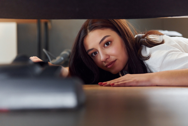 ベッドのしたの掃除をする女性
