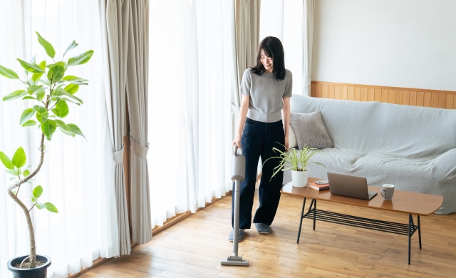 スティックタイプの掃除機を使う主婦